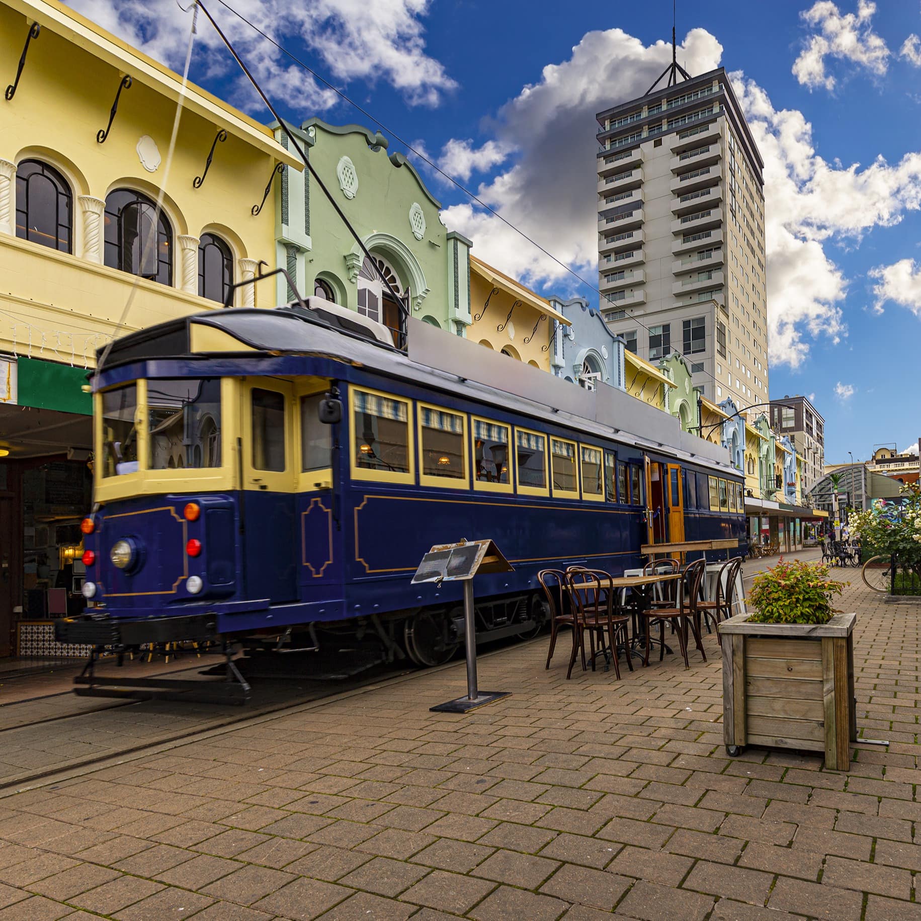 Tram in Christchurch along New Regent Street with colourful buildings lining a brick walkway