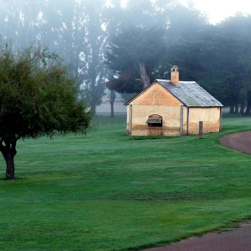 Former blacksmith cottage in Australian countryside with morning fog rising and a winding road