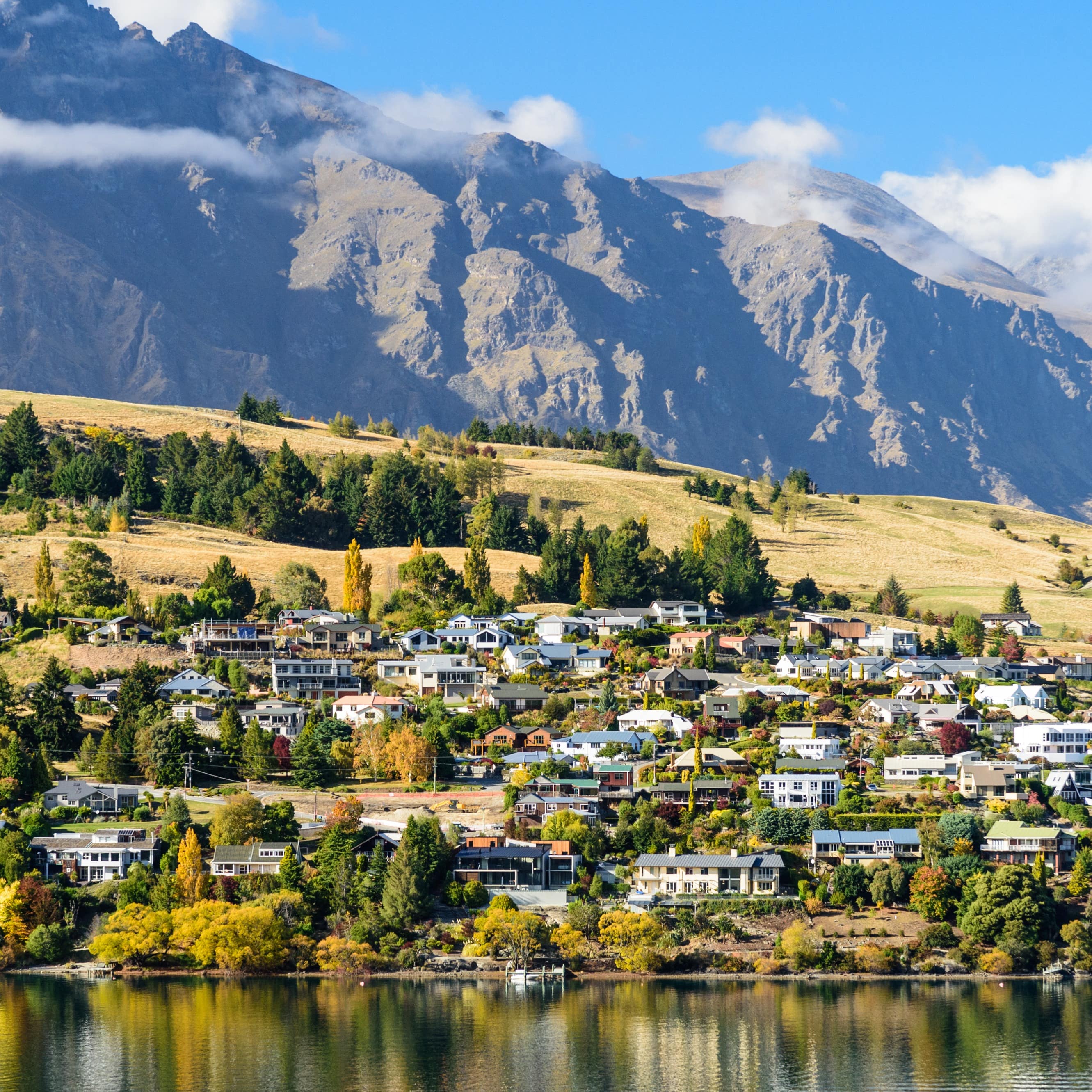 Landscape of Queenstown, New Zealand displays water, village and tall mountains