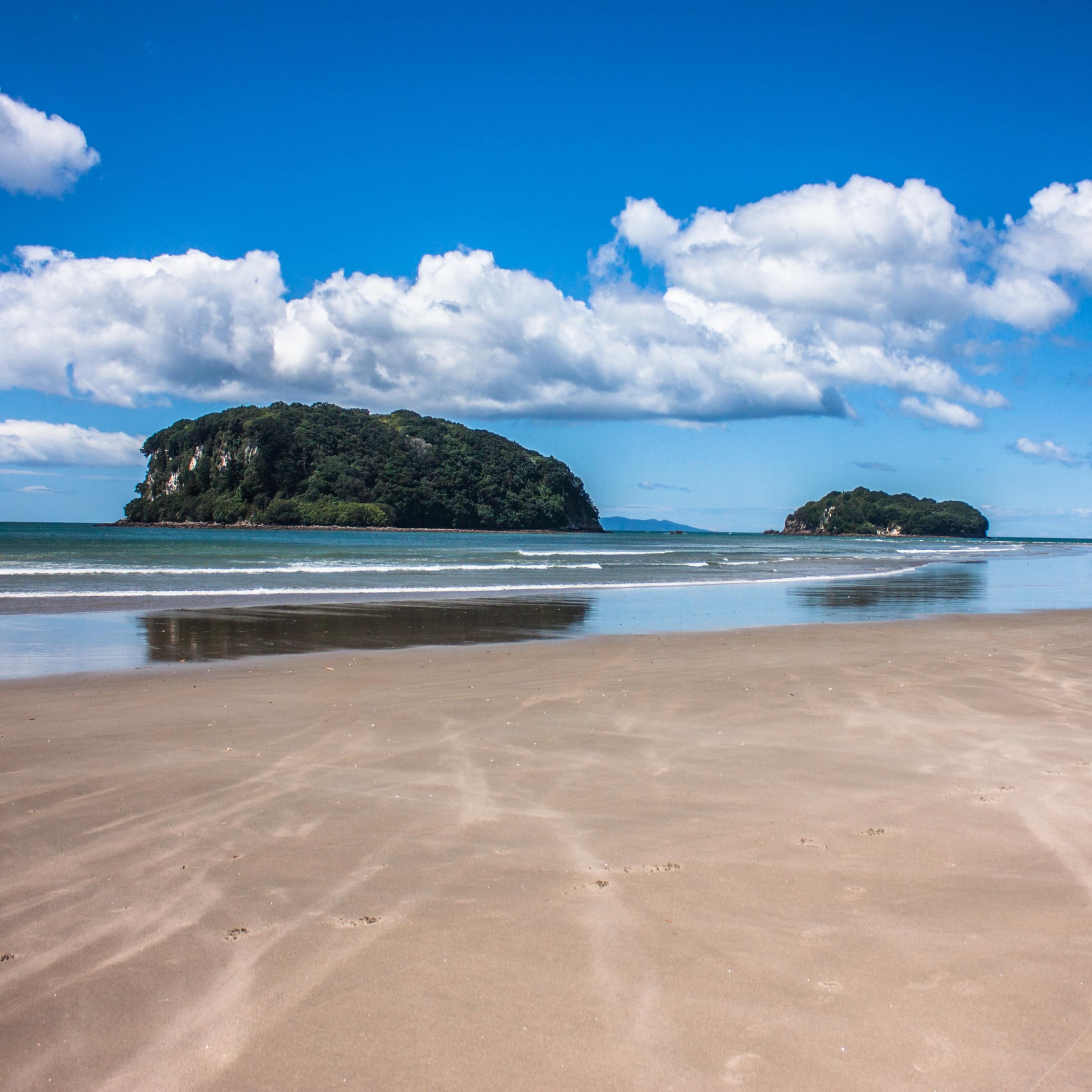 Sandy shore and view of distant island and bright blue sky