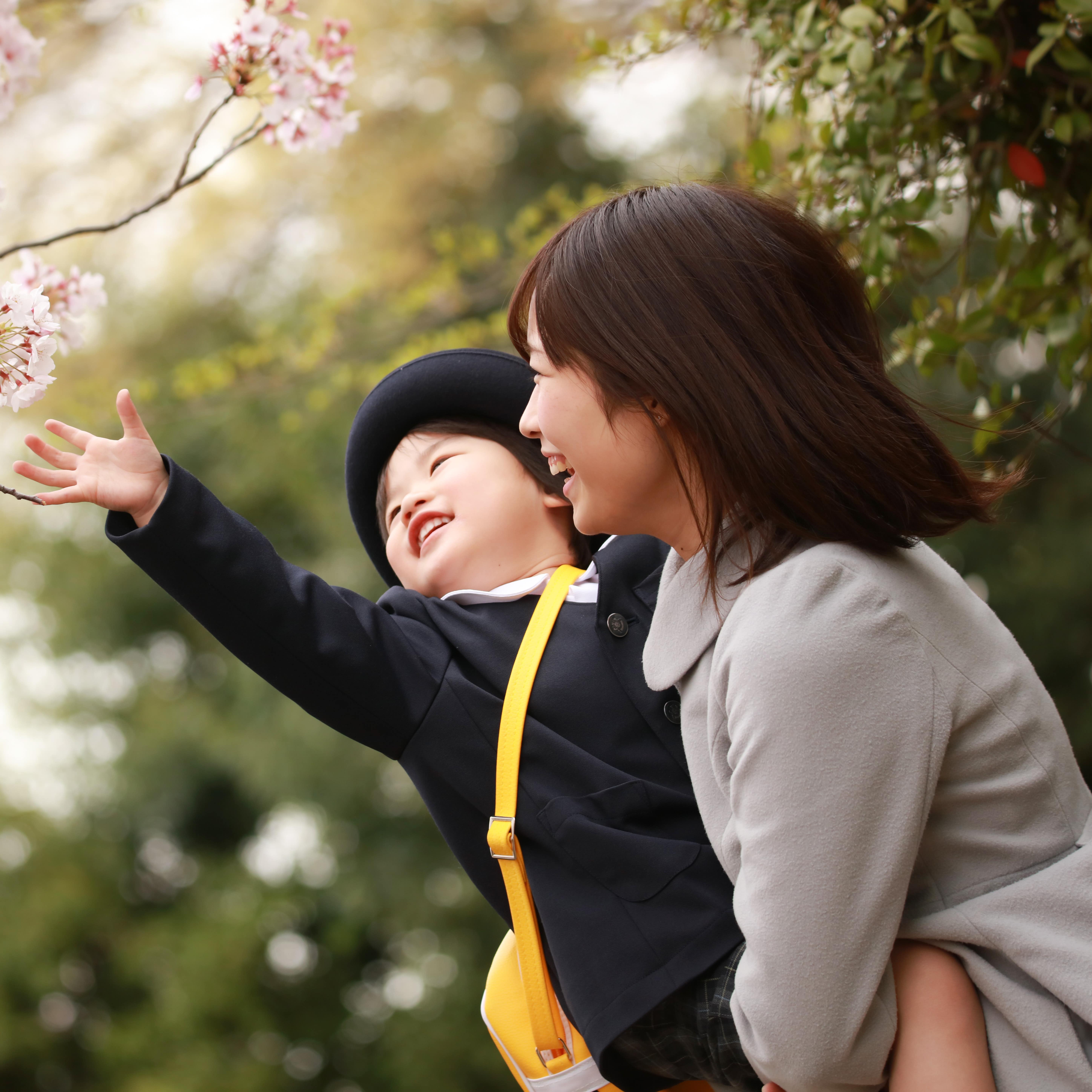 Mother holding child by cherry blossom tree