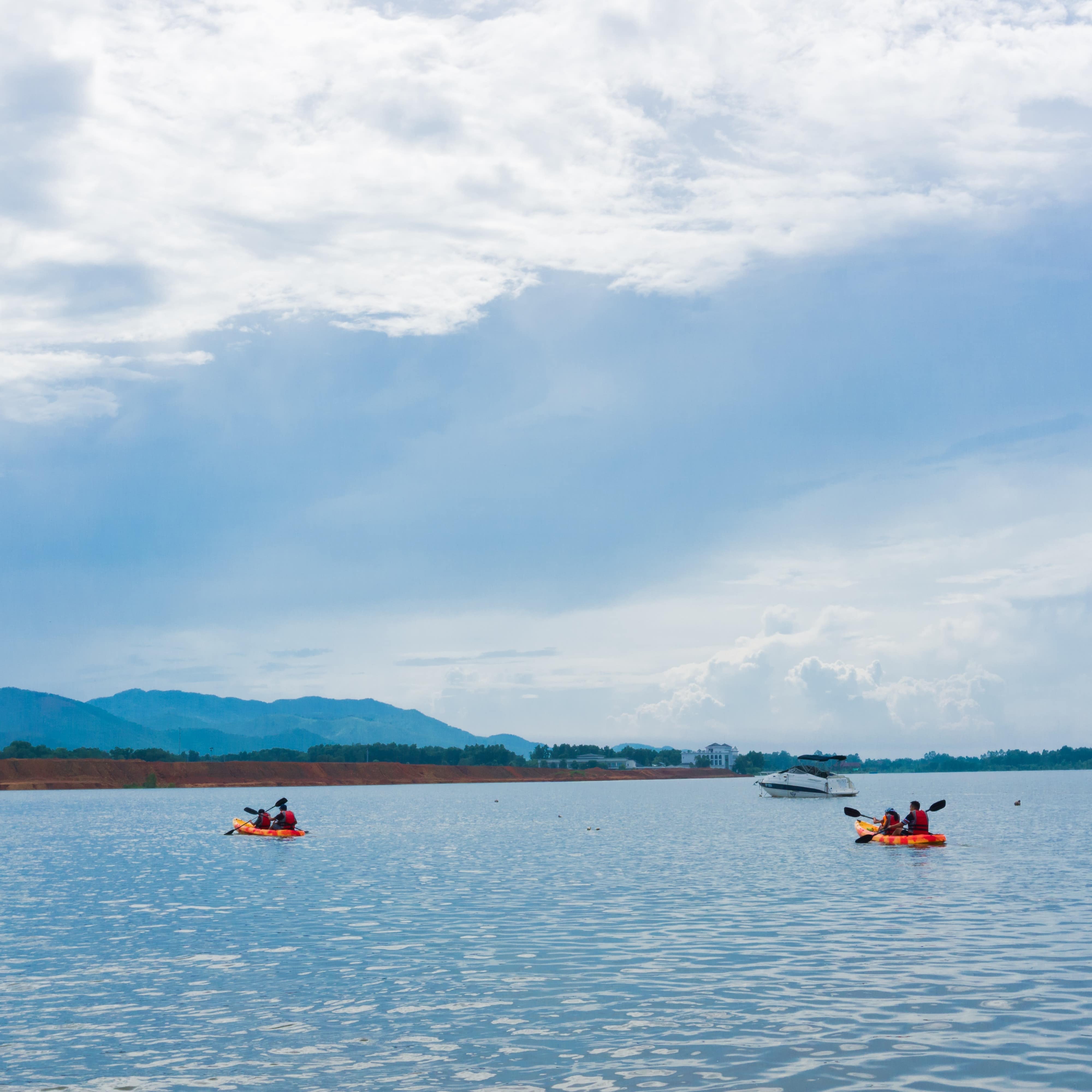 Families riding in kayaks on the water under a blue sky