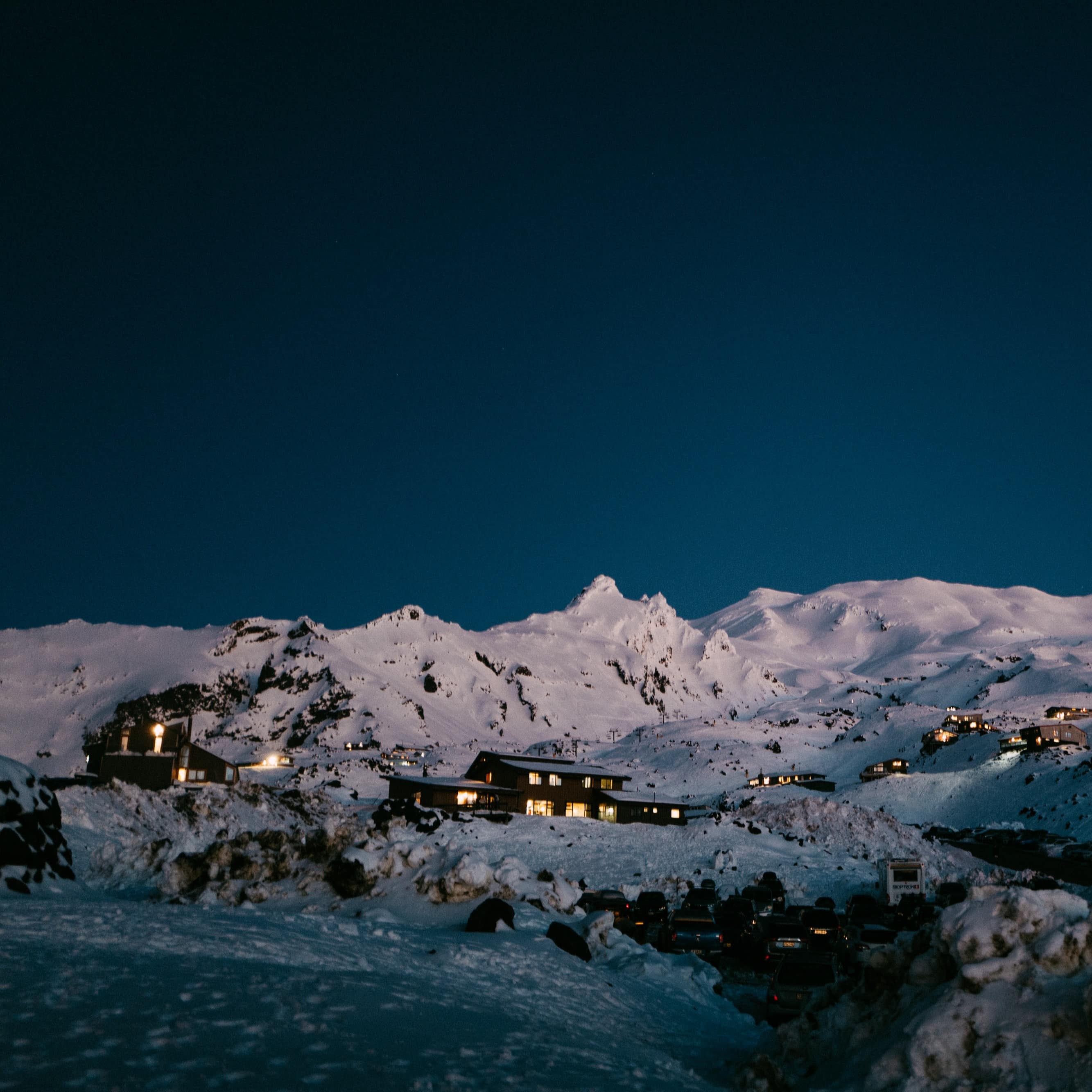 Snowy Mount Ruapehu at night with homes and lodges lit up on the mountainside