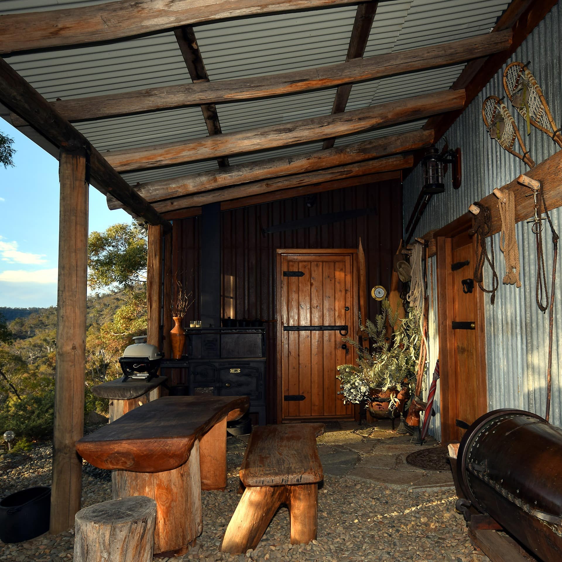 Rustic, covered patio space with mountain views, metal siding and exposed wood beams, natural wood table and barn decor.