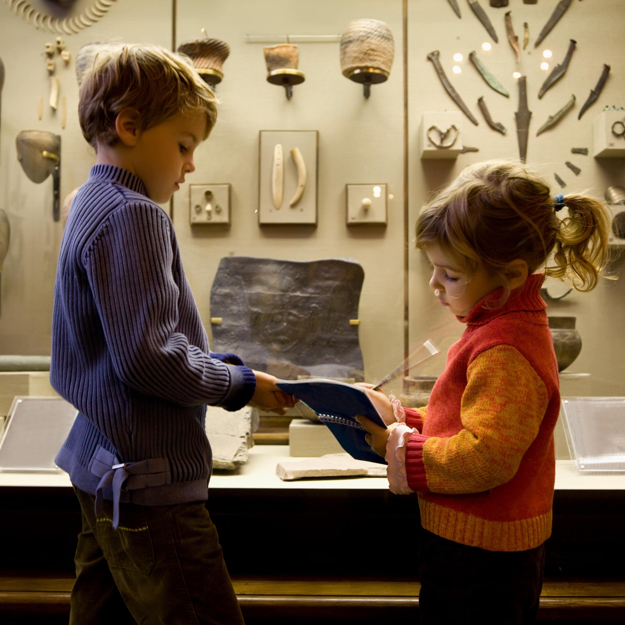 Little boy and girl taking notes at artifact museum