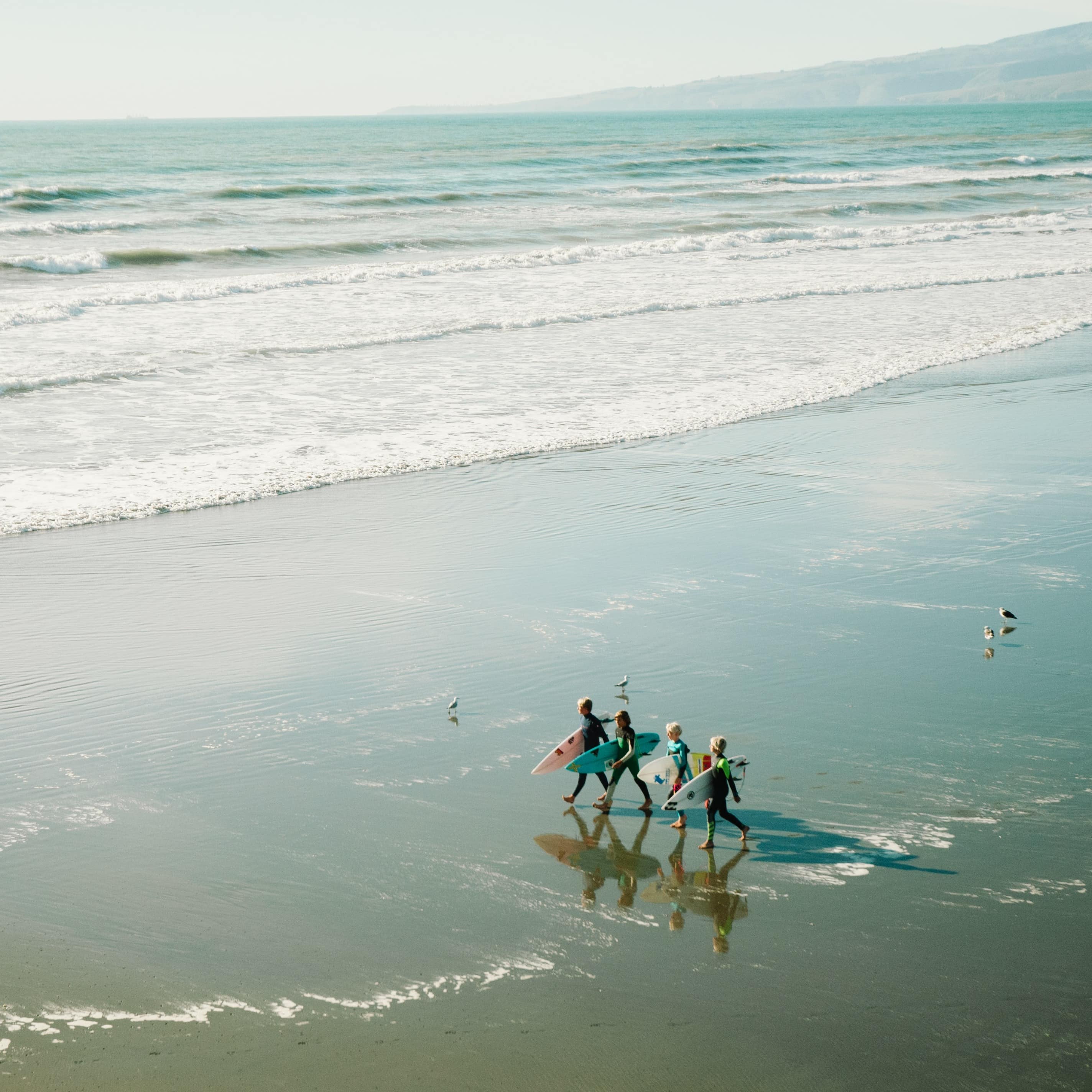 Family carrying surfboards and walking on the shore of a beach