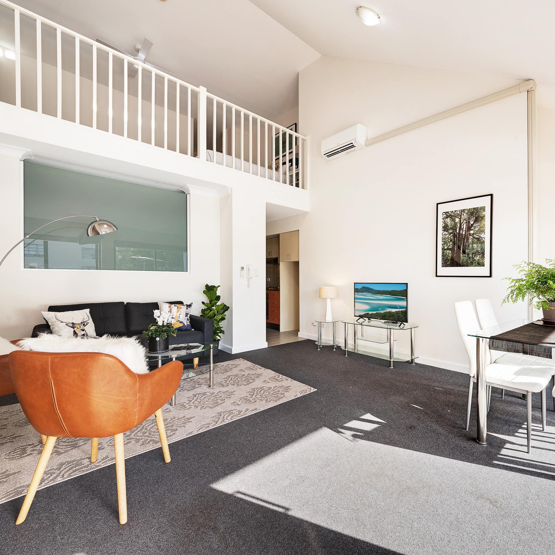 Living area of spacious self-contained apartment with sofa, leather chairs and dining set