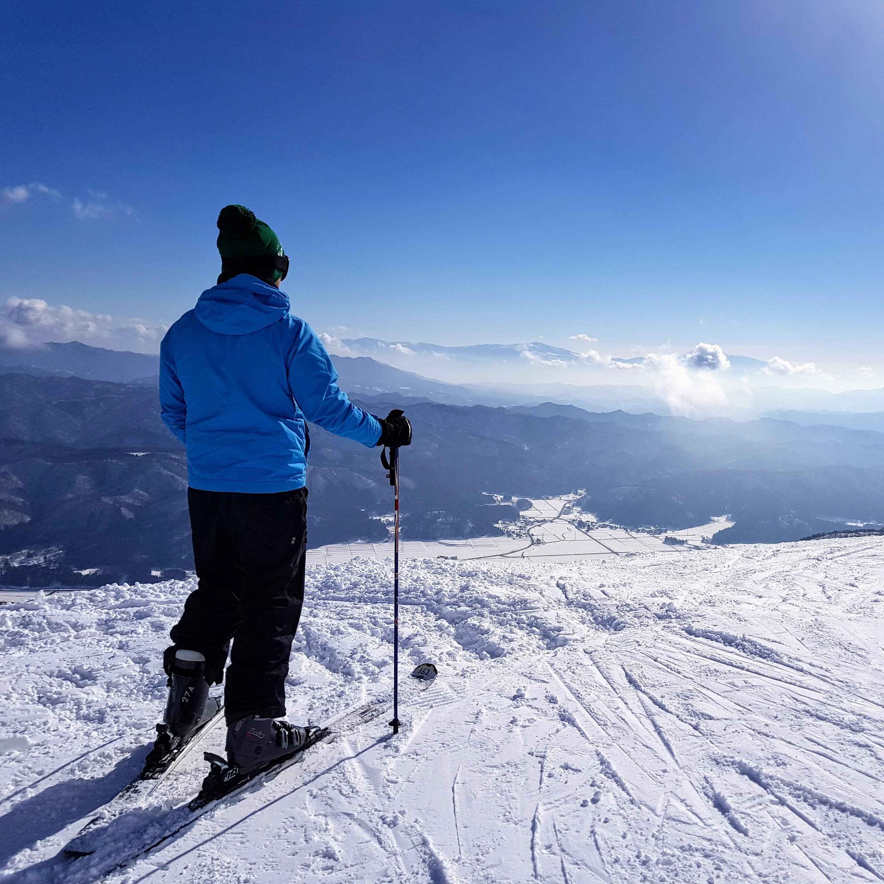 Skier standing on a snow-covered cliff overlooking the mountains and clouds