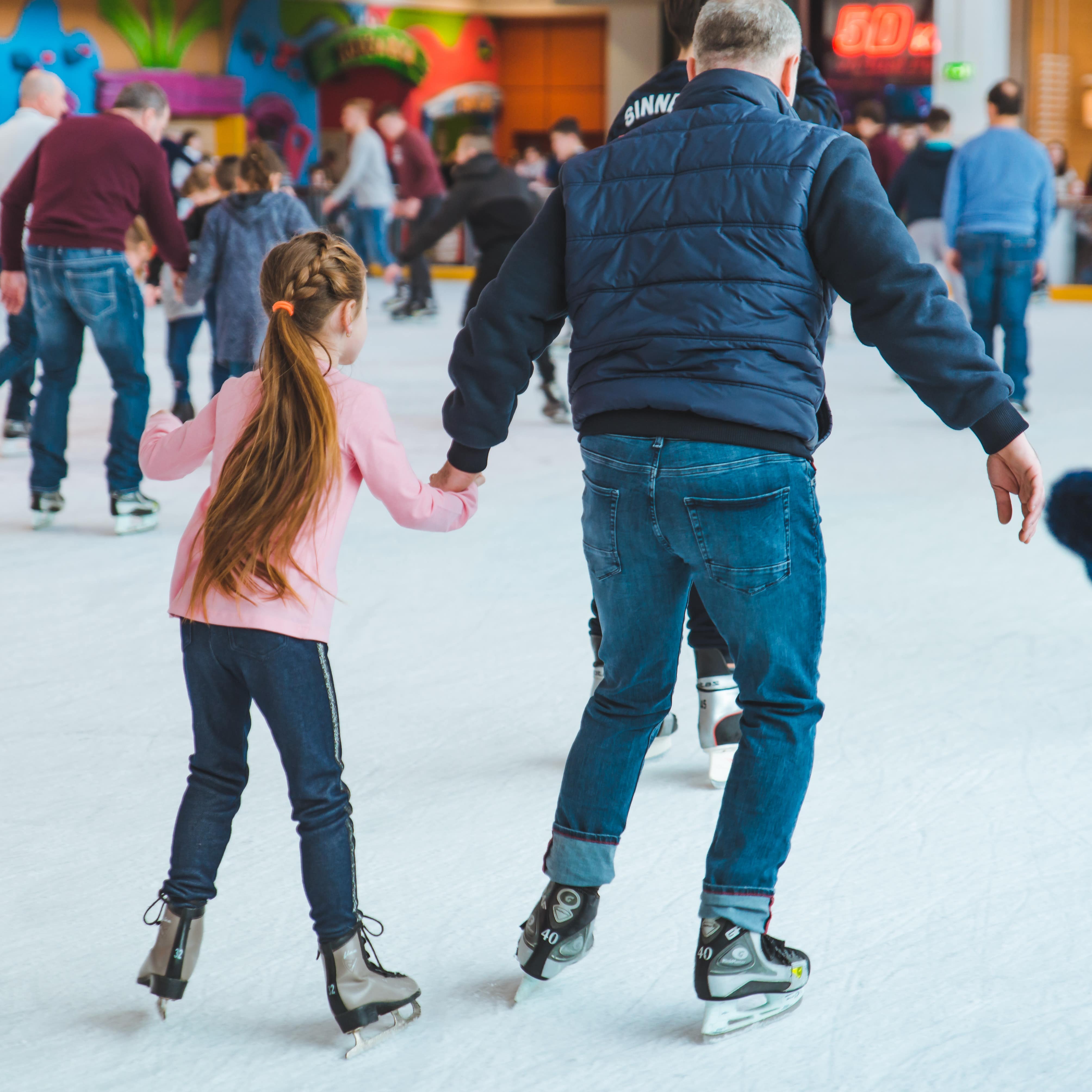Rear view of man and girl ice skating