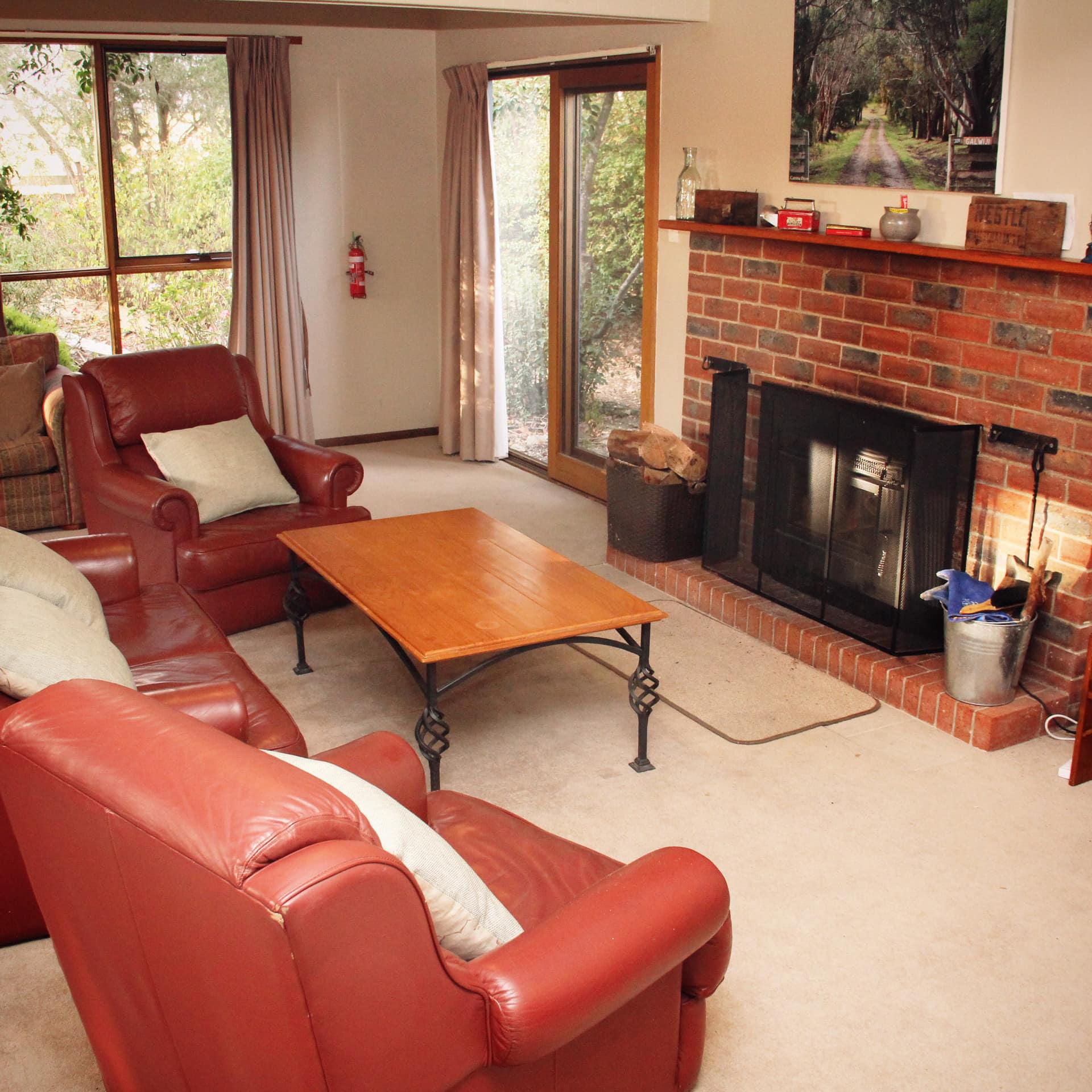 Interior of 6-bedroom farmhouse with red leather chairs and wood-burning fireplace