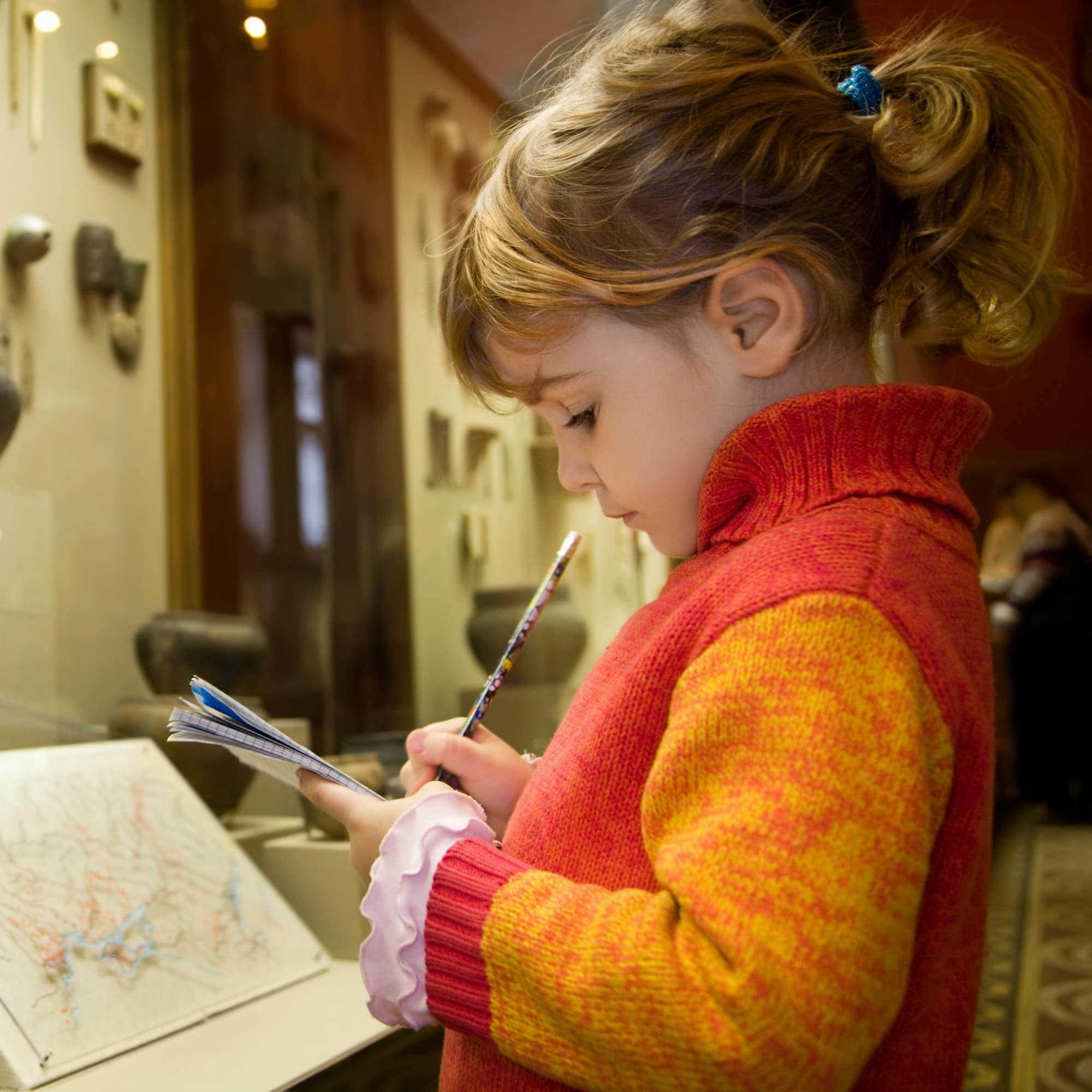 Little girl taking notes at museum exhibit