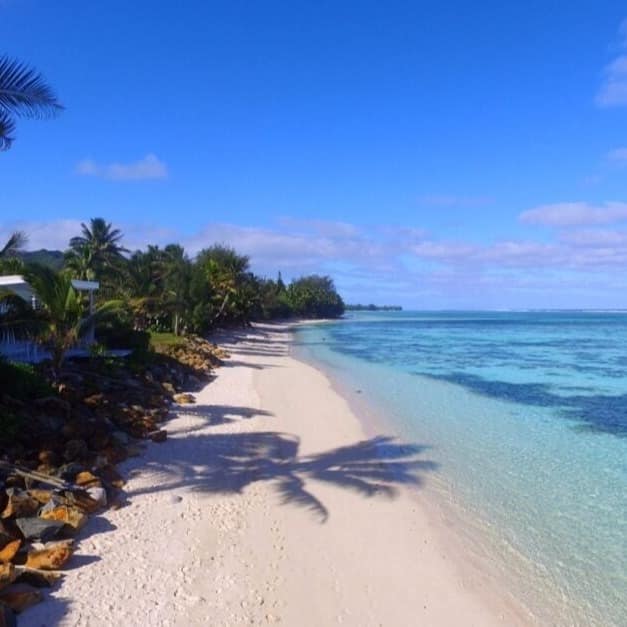 Stretch of beach showing rows of the land, the sand and the bright blue water across the road from an apartment