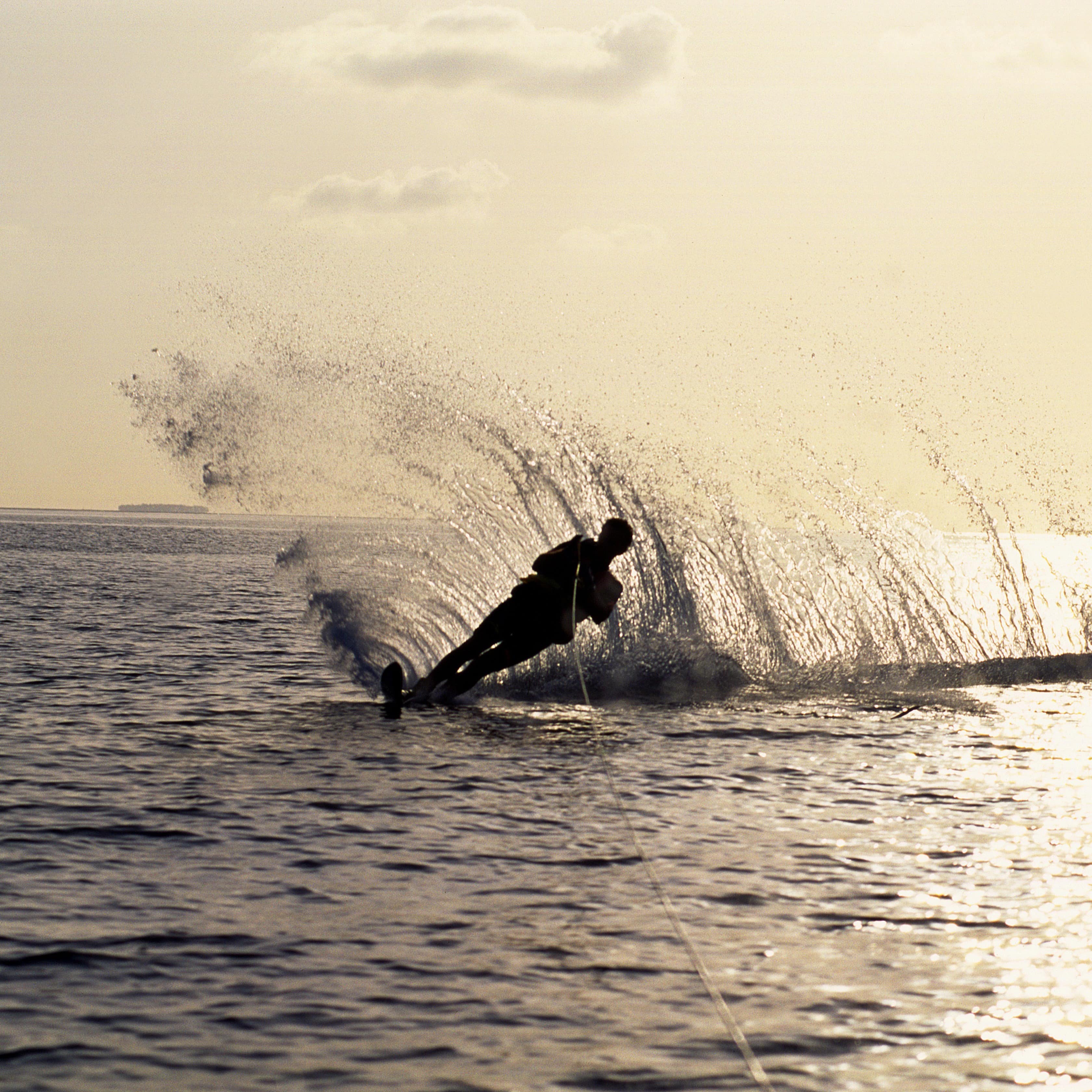 A man jet skiing on a lake at sunset.